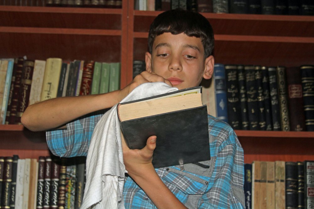 Chief Librarian, 14 year-old Amjad cleans a book _ Credit Daraya Council Media Team